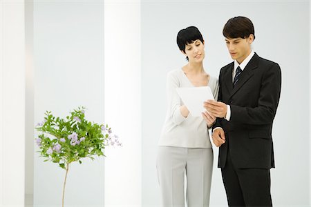 Male and female business partners standing side by side, discussing document Foto de stock - Sin royalties Premium, Código: 695-05779240