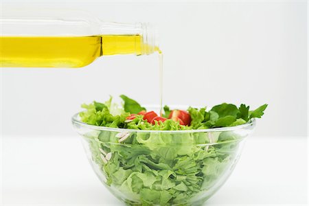 Olive oil being poured onto salad, close-up Fotografie stock - Premium Royalty-Free, Codice: 695-05779261