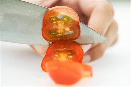 slicing fruit - Woman slicing tomato with knife, cropped view of hand Stock Photo - Premium Royalty-Free, Code: 695-05779270