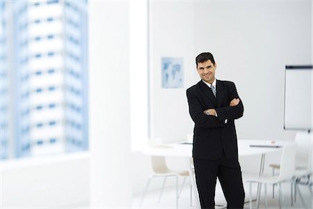 standing downtown - Businessman standing in meeting room with arms crossed, smiling at camera Stock Photo - Premium Royalty-Free, Code: 695-05779273