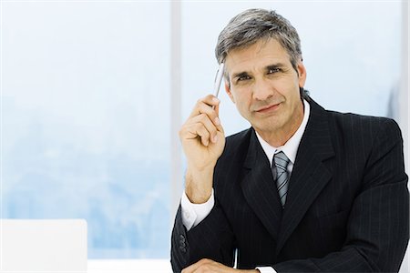 Businessman holding pen up to head, portrait Stock Photo - Premium Royalty-Free, Code: 695-05779294