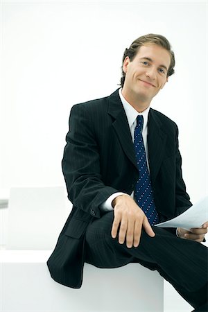 Businessman sitting, hand on knee, smiling at camera Stock Photo - Premium Royalty-Free, Code: 695-05779337