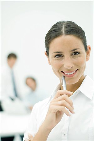 Female professional smiling at camera, holding pen up to chin, portrait Stock Photo - Premium Royalty-Free, Code: 695-05779347