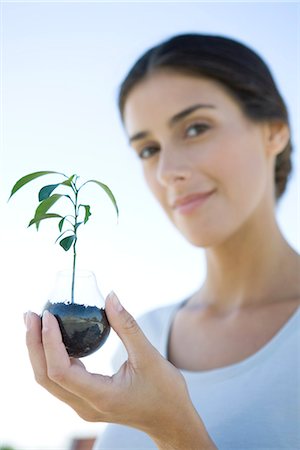 simsearch:695-05779538,k - Woman holding potted seedling, smiling at camera, focus on foreground Stock Photo - Premium Royalty-Free, Code: 695-05779393