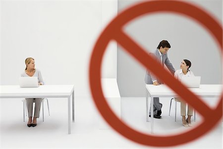 Warning sign across chatting male and female office workers, female colleague watching Stock Photo - Premium Royalty-Free, Code: 695-05779416