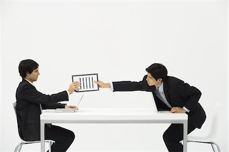 studio graphic - Two business associates sitting face to face at desk, one hand document to the other Stock Photo - Premium Royalty-Free, Code: 695-05779424
