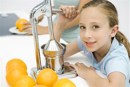 squeezing (make juice) - Little girl making fresh orange juice with citrus press, mother in background Stock Photo - Premium Royalty-Free, Code: 695-05779457