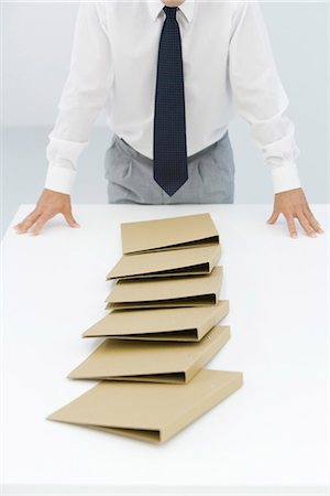 falling down in the office - Binders lying on table after a chain reaction of being pushed over, cropped view of businessman Stock Photo - Premium Royalty-Free, Code: 695-05779464