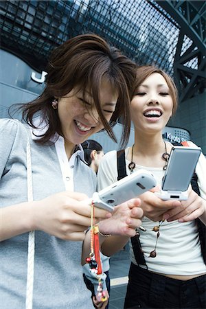 smartphones play - Female friends looking at cell phones and laughing Stock Photo - Premium Royalty-Free, Code: 695-05779589