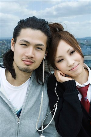 Young couple sharing earphones, smiling Stock Photo - Premium Royalty-Free, Code: 695-05779590