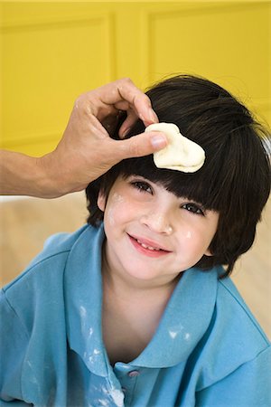 parent child messy cooking - Parent holding dough against little boy's head, cropped Stock Photo - Premium Royalty-Free, Code: 695-05779864