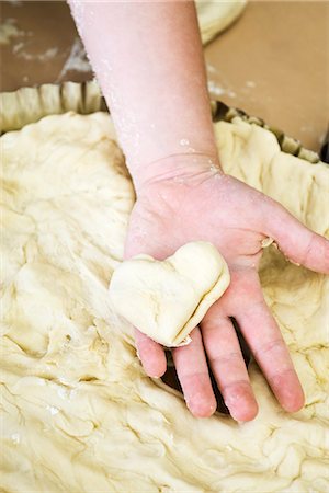 Child's hand holding heart shaped piece of dough Foto de stock - Sin royalties Premium, Código: 695-05779867