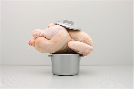 Concept de restauration, poulet entier cru au sommet du pot trop petit Photographie de stock - Premium Libres de Droits, Code: 695-05779892