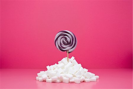 Food concept, lollipop sticking out from pile of sugar cubes Foto de stock - Royalty Free Premium, Número: 695-05779927