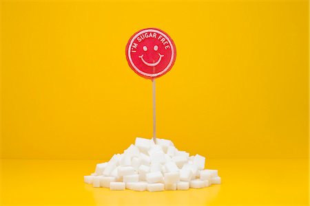 Food concept, sugar-free lollipop sticking out of pile of sugar cubes Foto de stock - Royalty Free Premium, Número: 695-05779932