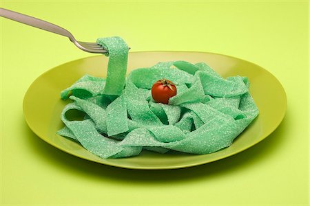 Food concept, plate of green gummy candy arranged like pasta, topped with cherry tomato Stock Photo - Premium Royalty-Free, Code: 695-05779948