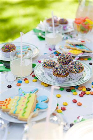 serpentin - Biscuits glacés et cupcakes sur table décoré de banderoles et de bonbons Photographie de stock - Premium Libres de Droits, Code: 695-05779970