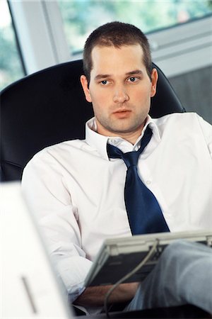 Man with feet up on office desk, typing on computer keyboard set on lap Stock Photo - Premium Royalty-Free, Code: 695-05770011
