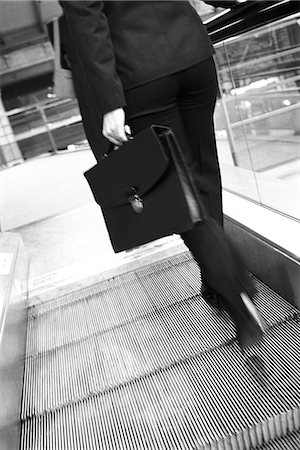 Businesswoman ascending escalator, rear view Stock Photo - Premium Royalty-Free, Code: 695-05770023