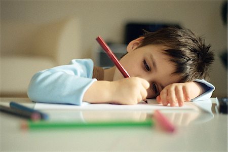 Little boy resting head on arm, drawing with colored pencils Stock Photo - Premium Royalty-Free, Code: 695-05770152