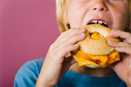 Boy eating bagel and cheese sandwich, cropped Stock Photo - Premium Royalty-Free, Code: 695-05770284