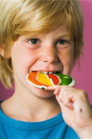 Boy biting into lollipop Foto de stock - Sin royalties Premium, Código: 695-05770288