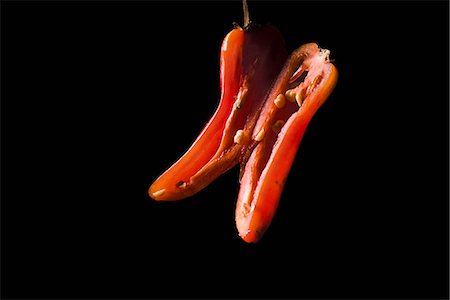 Red chili pepper sliced in half lengthwise, on black background Foto de stock - Sin royalties Premium, Código: 695-05770347