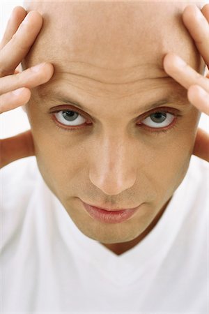 Bald man holding head, looking at camera Stock Photo - Premium Royalty-Free, Code: 695-05770385