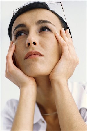 Woman holding head, looking up Stock Photo - Premium Royalty-Free, Code: 695-05770417