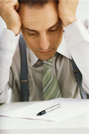 Man holding head, staring at document Foto de stock - Sin royalties Premium, Código: 695-05770411