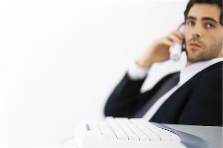 receiver - Businessman on phone call, looking away, keyboard in foreground Stock Photo - Premium Royalty-Free, Code: 695-05770439