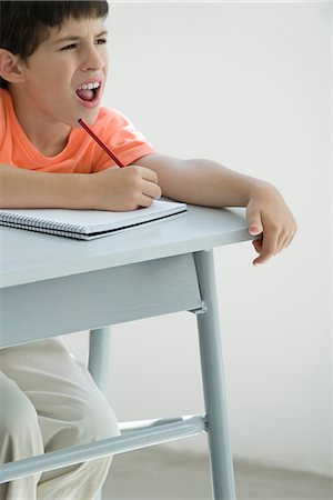 Elementary school student taking notes in classroom, squinting at board Stock Photo - Premium Royalty-Free, Code: 695-05770507