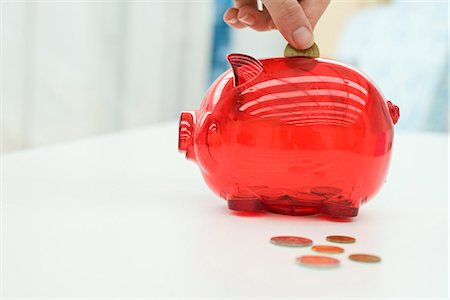 people depositing in the bank - Person putting change in piggy bank, cropped Stock Photo - Premium Royalty-Free, Code: 695-05770541