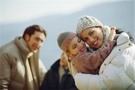 Little girl embracing mother, family in background Stock Photo - Premium Royalty-Free, Code: 695-05770594