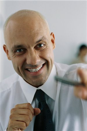 Businessman clenching fists, smiling at camera Stock Photo - Premium Royalty-Free, Code: 695-05770612