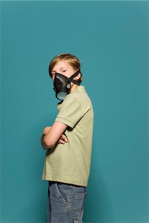 defiance child - Boy wearing gas mask, arms folded, looking over shoulder at camera Stock Photo - Premium Royalty-Free, Code: 695-05770681