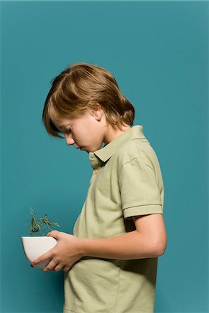 side view of a boy - Boy holding wilted potted plant, head down Stock Photo - Premium Royalty-Free, Code: 695-05770682