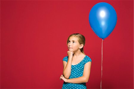 Girl with hand under chin, balloon suspended behind her Stock Photo - Premium Royalty-Free, Code: 695-05770690