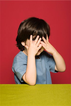 simsearch:695-03379065,k - Little boy covering face with hands, peeking through fingers at camera Foto de stock - Royalty Free Premium, Número: 695-05770705