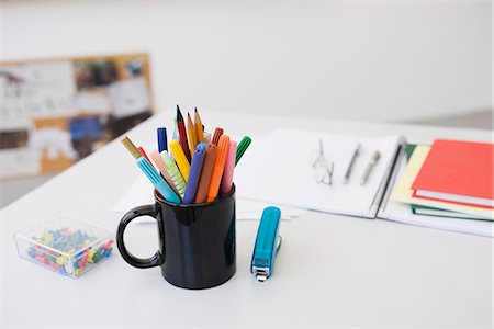 Markers, pens and pencils in mug on desk with school supplies Stock Photo - Premium Royalty-Free, Code: 695-05770711