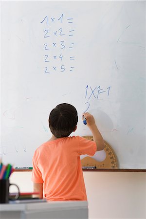 scuola elementare - Elementary school student doing math equation on whiteboard, rear view Fotografie stock - Premium Royalty-Free, Codice: 695-05770722