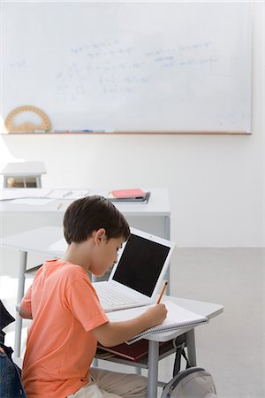 electronic school desk - Elementary school student busy doing assignment in classroom Stock Photo - Premium Royalty-Free, Code: 695-05770736