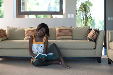 simsearch:633-08151062,k - Young woman sitting on living room floor reading book Stock Photo - Premium Royalty-Free, Code: 695-05770748