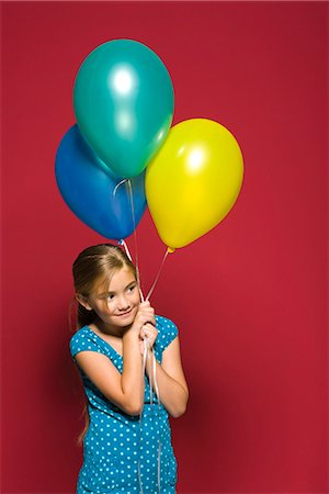 Girl holding balloons, looking away, smiling Stock Photo - Premium Royalty-Free, Code: 695-05770758