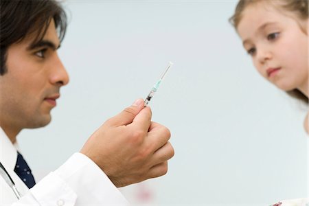 Pediatrician showing little girl syringe Stock Photo - Premium Royalty-Free, Code: 695-05770762