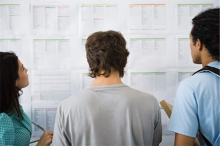 people looking at notice board - College students checking bulletin board for classroom assignments, rear view Foto de stock - Sin royalties Premium, Código: 695-05770779