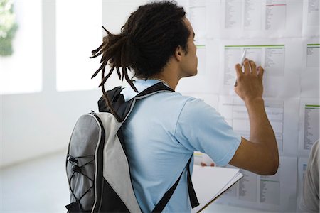 student back pack - Male college student checking bulletin board Stock Photo - Premium Royalty-Free, Code: 695-05770783