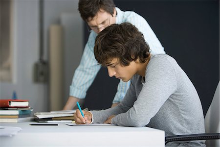 Male college student working with teacher's assistance Stock Photo - Premium Royalty-Free, Code: 695-05770804
