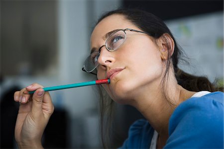 pencil ideas - Woman thinking, looking away, pen in mouth Stock Photo - Premium Royalty-Free, Code: 695-05770812