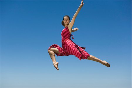 striped woman dress - Young woman leaping, midair Stock Photo - Premium Royalty-Free, Code: 695-05770853